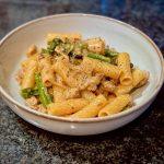 Bowl of pasta with sausage and broccolini with a creamy sauce.