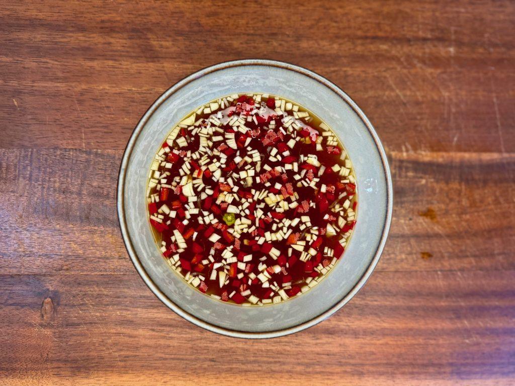 Vietnamese nước chấm dipping sauce in a bowl on a wooden board.
