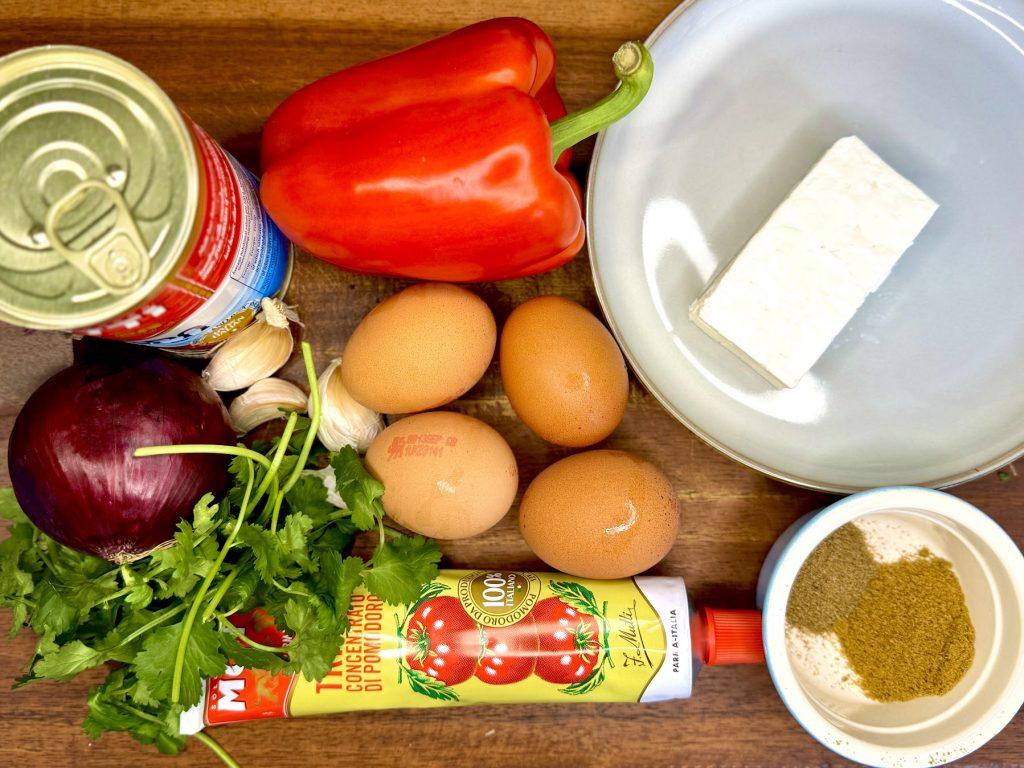 Shakshuka ingredients displayed on a wooden board.