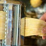 Fresh pasta being rolled in a pasta machine