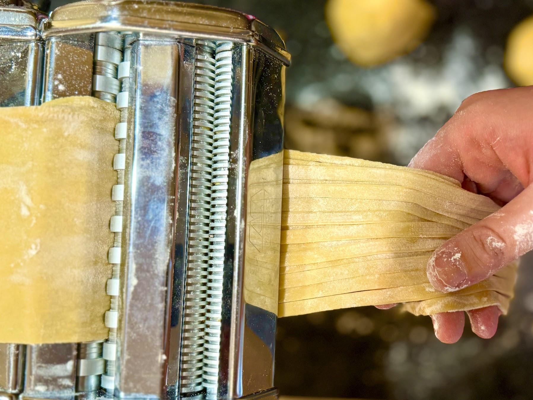 Fresh pasta being rolled in a pasta machine