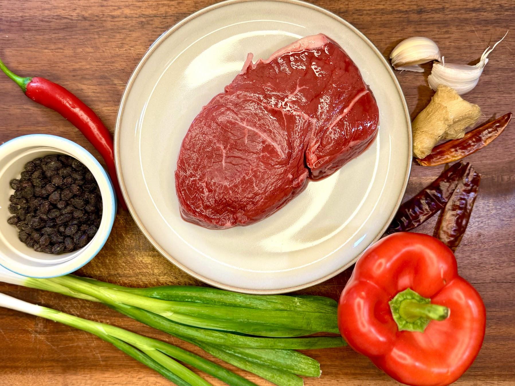 Steak, black beans and vegetables on a wooden board.