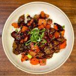 Bowl of Hunan Beef on a wooden board.
