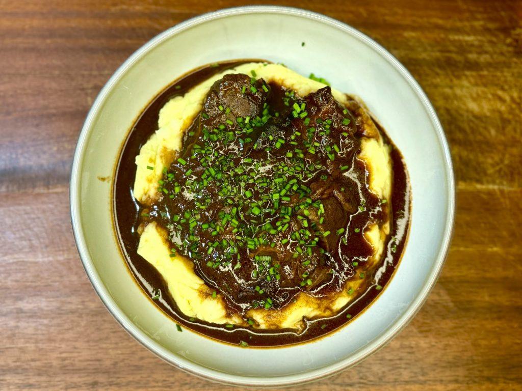 Bowl of slow cooked beef shin in red wine sauce on mustard mashed potatoes