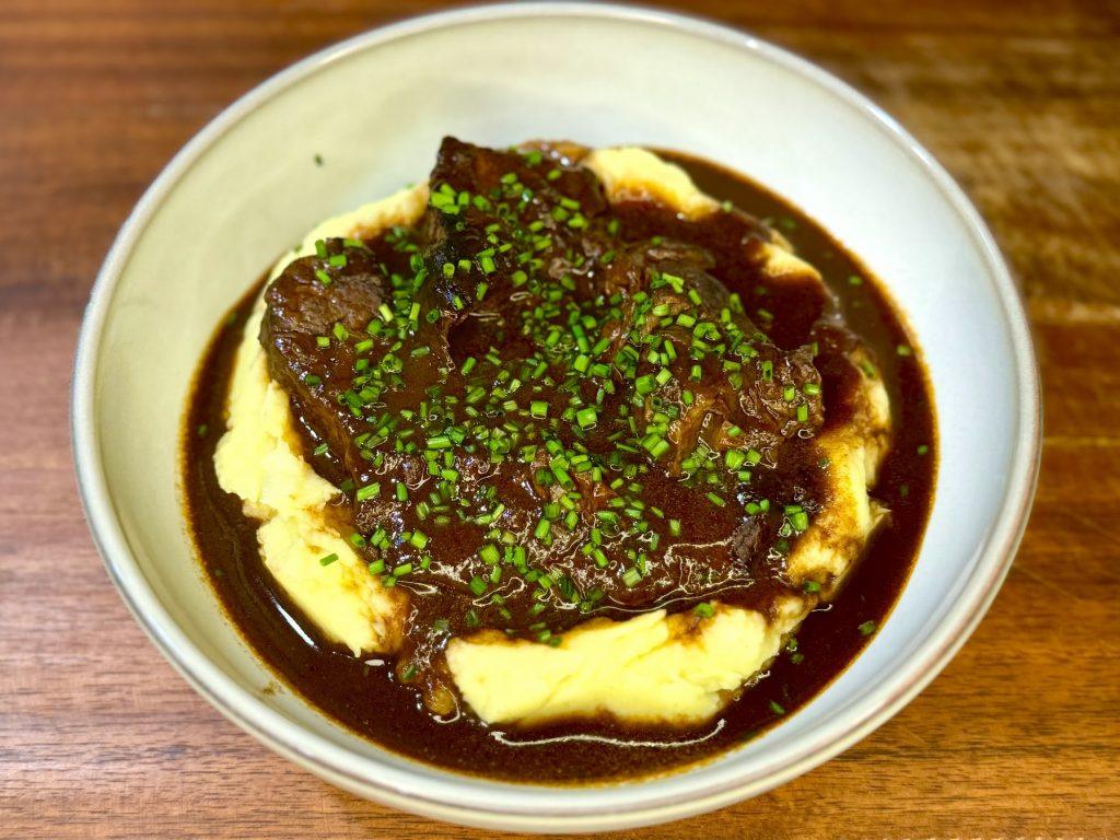 Bowl of slow cooked beef shin in red wine sauce on mustard mashed potatoes
