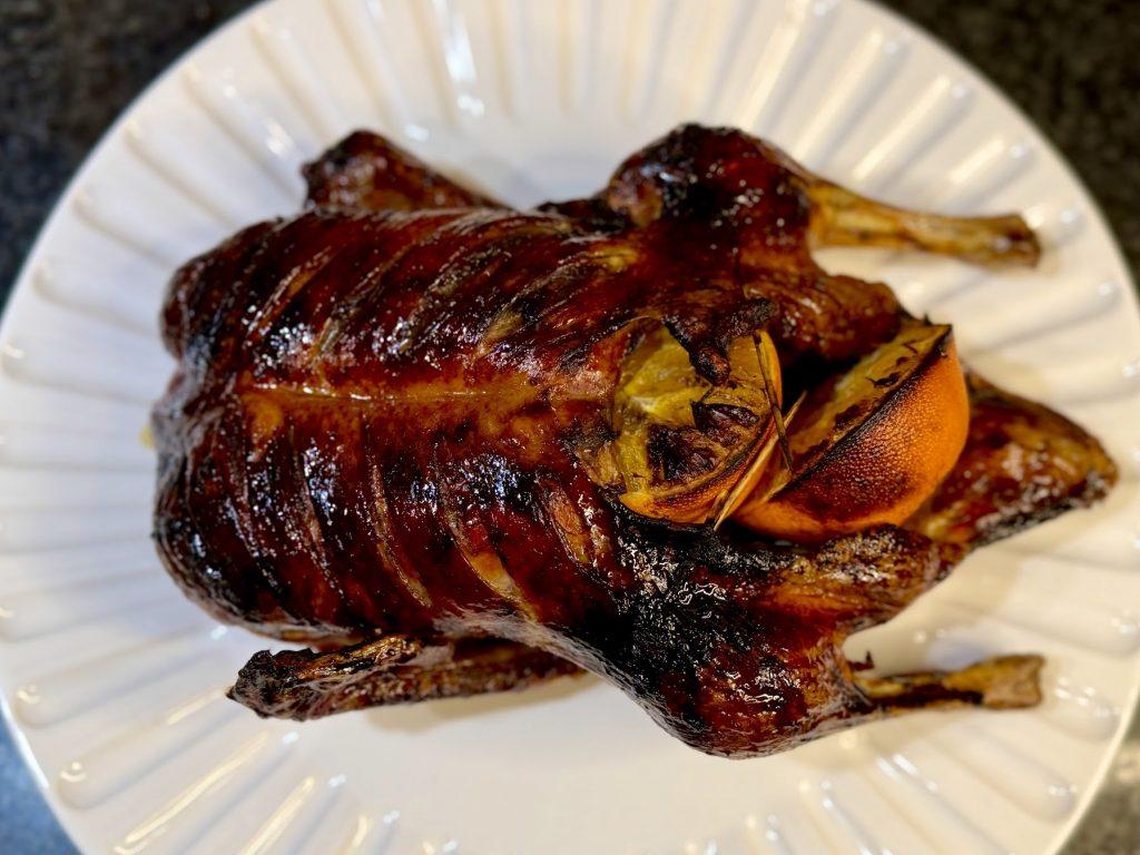A roasted duck stuffed wih oranges on a plate.