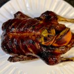 A roasted duck stuffed wih oranges on a plate.