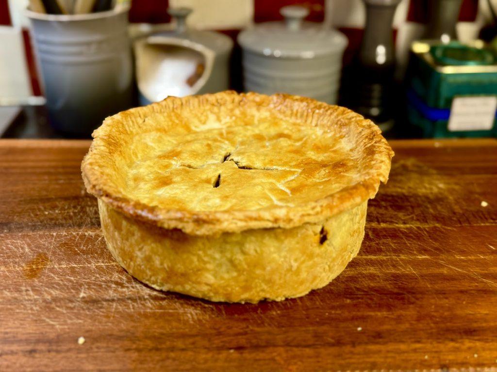 Steak & ale pie on a wooden chopping board