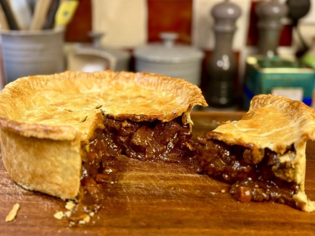 Sliced steak & ale pie on a wooden chopping board