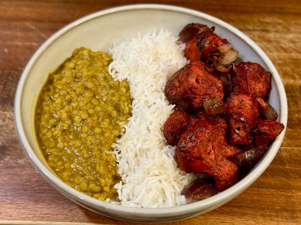 A bowl of chicken tikka, rice and tarka daal