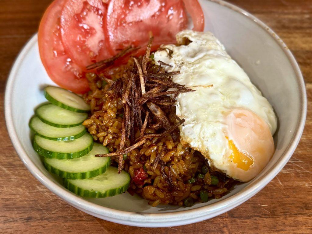 Bowl of nasi goreng with salad and a fried egg